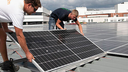 Twee installateurs leggen zonnepanelen op het dag van Ziekenhuis Gelderse Vallei